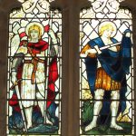 Stained glass window showing two standing figures, one haloed and one in armour.