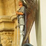 Painted carved angel or saint figure mounted high on a church pillar.