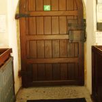 Heavy wooden church door with iron hinges and latch.